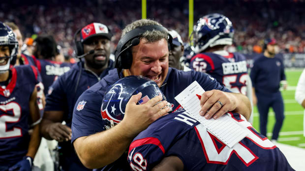 Houston Texans linebacker Christian Harris (48) is hugged by his coach after a pick six during the third quarter in a 2024 AFC wild card game at NRG Stadium.