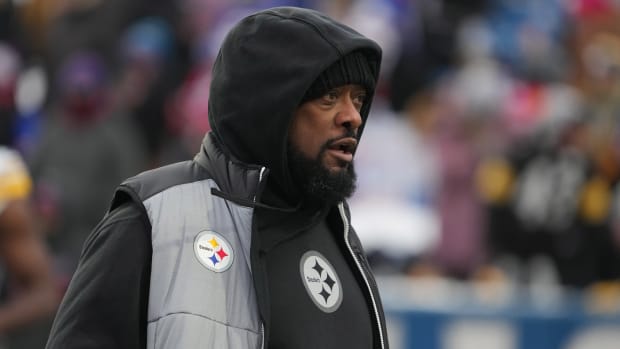Mike Tomlin stands on the field with his hood up