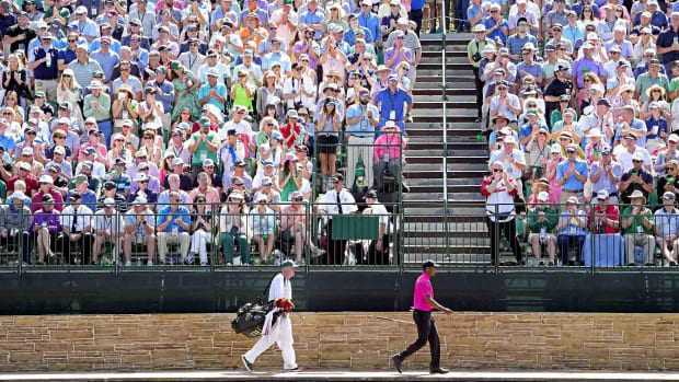 Tiger Woods and caddie Joe LaCava walk across the Sarazen Bridge at Augusta National during Round 1 of the 2022 Masters.