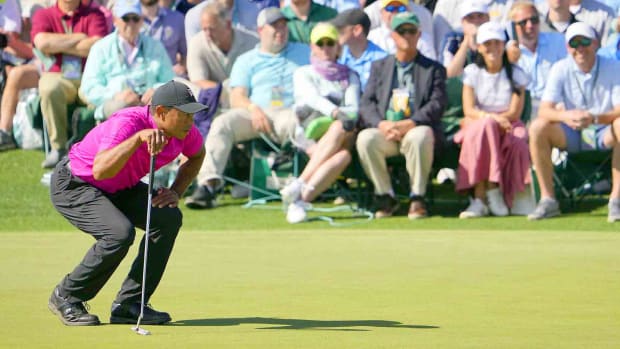 Tiger Woods crouches to read a putt on the 18th hole in the first round of the 2022 Masters.