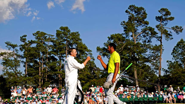 Mark Urbanek and Tony Finau fist-bump on the 18th green during the final round of the Masters.