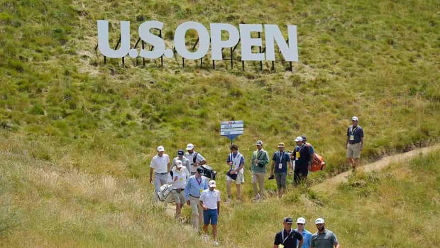Players and officials walk under a sign at the fourth hole of Los Angeles Country Club in a practice round for the 2023 U.S. Open.
