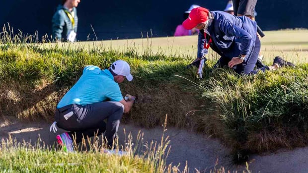Rory McIlroy and a USGA rules official examine an embedded ball situation at the 2023 U.S. Open.