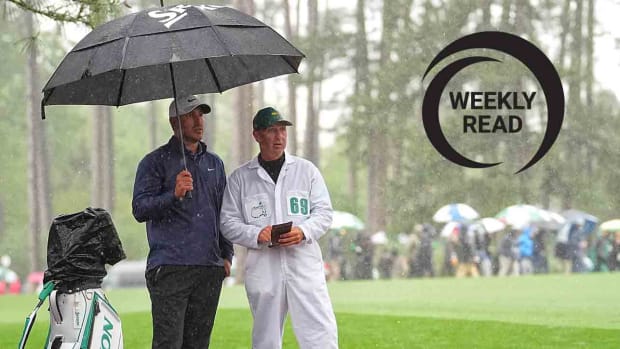 Brooks Koepka and caddie Ricky Elliott are pictured in the rain at the 2023 Masters.
