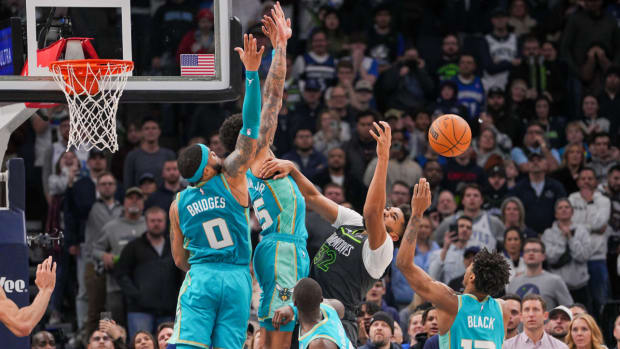 Timberwolves center Karl-Anthony Towns attempts a basket while Hornets players defend him.