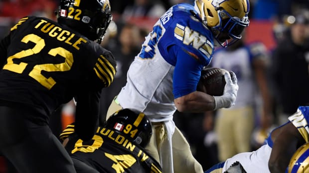 Nov 24, 2019; Calgary, Alberta, CAN; Winnipeg Blue Bombers running back Andrew Harris (33) escapes the tackles of Hamilton Tiger-Cats defensive end Lorenzo Mauldin IV (94) and Justin Tuggle (22) in the second half during the 107th Grey Cup championship football game at McMahon Stadium. Mandatory Credit: Eric Bolte-USA TODAY Sports  