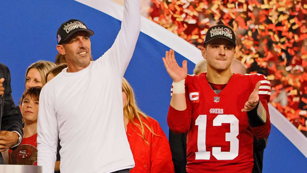 49ers head coach Kyle Shanahan, left, waves to fans while quarterback Brock Purdy claps on stage after winning the NFC championship