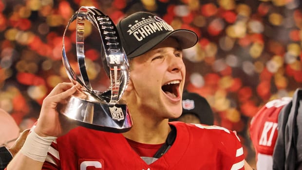 Brock Purdy smiles with his mouth open holding the NFC conference championship trophy
