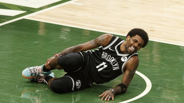 Brooklyn Nets guard Kyrie Irving (11) grabs his leg after being injured during the second quarter against the Milwaukee Bucks