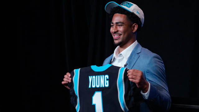 Bryce Young holds up a jersey depicting his draft position at Bank of America Stadium.