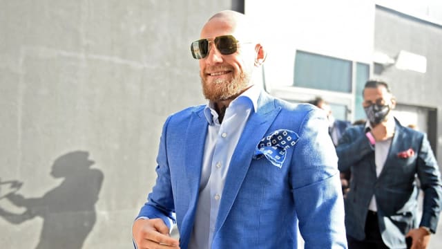UFC legend Conor McGregor walks outside with a blue suit on.