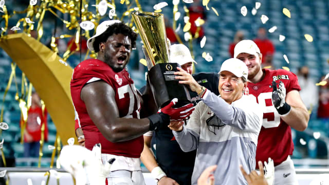 Alabama Crimson Tide head coach Nick Saban and offensive lineman Alex Leatherwood (70) celebrates with the CFP National Championship trophy after beating the Ohio State Buckeyes in the 2021 CFP Championship.