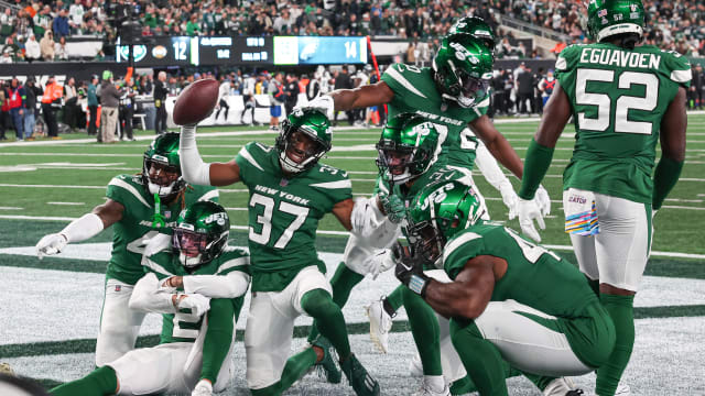 Jets' defense poses in celebration following an interception against the Eagles
