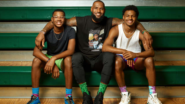 LeBron James, center, sits on bleachers with his arms around his kids: Bryce James, left, and Bronny James, right.
