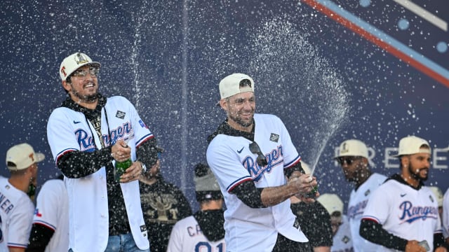 Texas Rangers starting pitchers Dane Dunning, left, and Nathan Eovaldi spray the crowd with champagne during the team's World Series championship celebration outside Globe Life Field.