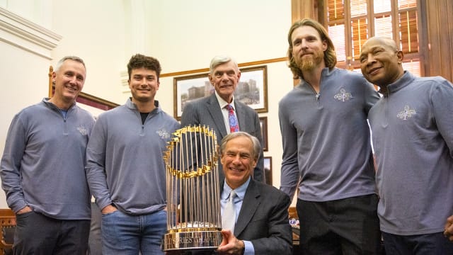 Governor Greg Abbott holds the World Series championship trophy on Thursday at the Capitol in Austin after presenting a congratulatory proclamation to members of the Texas Rangers following the team's first World Series. Abbott is flanked, from left, by Rangers television announcer Dave Raymond, minor league infielder Justin Foscue, Rangers owner Ray Davis, pitcher Jon Gray, and third base coach Tony Beasley.