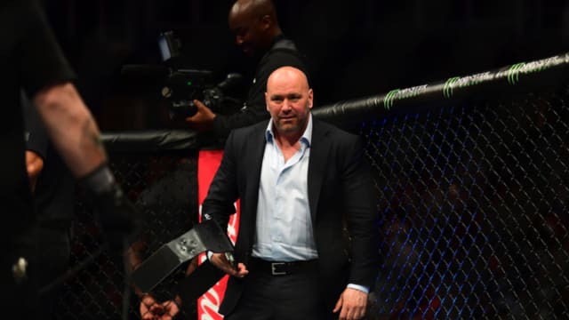 UFC CEO Dana White carries a championship to place on the winner's waist.