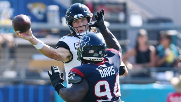 Jaguars quarterback Trevor Lawrence launches a pass to while being pressured by Houston Texans defensive tackle Khalil Davis.