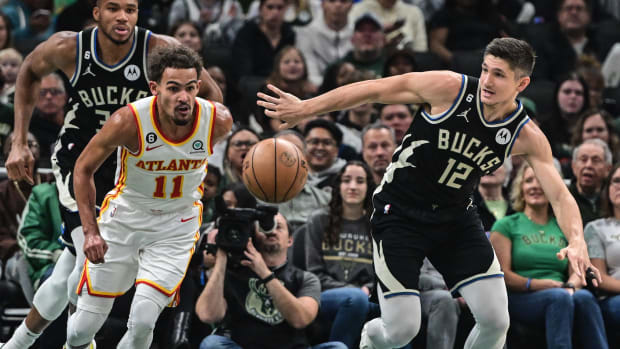 Hawks guard Trae Young and Bucks guard Grayson Allen reach for the ball.