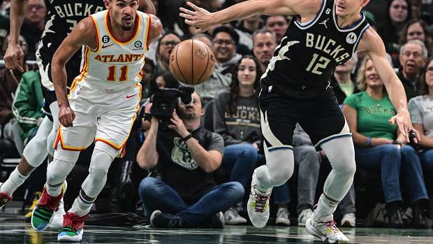 Hawks guard Trae Young and Bucks guard Grayson Allen reach for the ball.