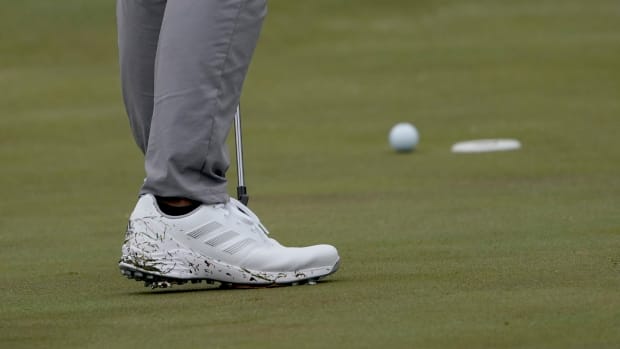Side view of white adidas golf shoes.