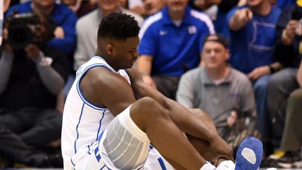 Duke Blue Devils forward Zion Williamson checks on his foot after falling.