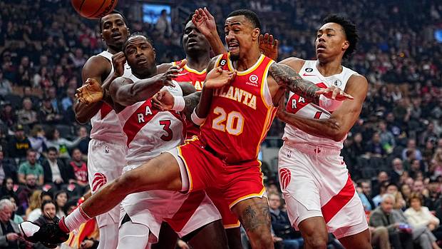 Hawks forward John Collins battles for the ball against Raptors defenders.