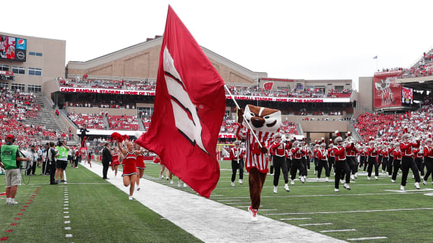 Bucky Badger running with a Wisconsin Badgers flag in pregame.