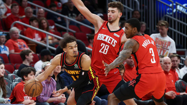 Hawks guard Trae Young attempts to pass the ball around Rockets defenders.