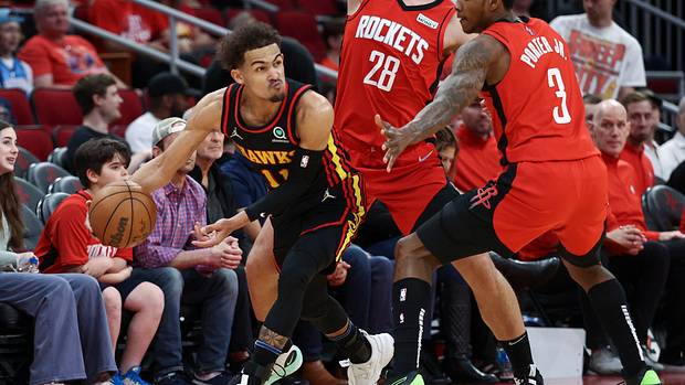 Hawks guard Trae Young attempts to pass the ball around Rockets defenders.