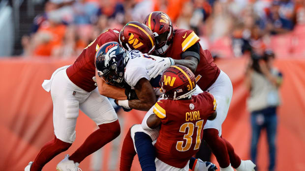 Denver Broncos wide receiver Courtland Sutton (14) is tackled by Washington Commanders safety Kamren Curl (31) and linebackers Cody Barton (57) and Jamin Davis (52) in the fourth quarter at Empower Field at Mile High.