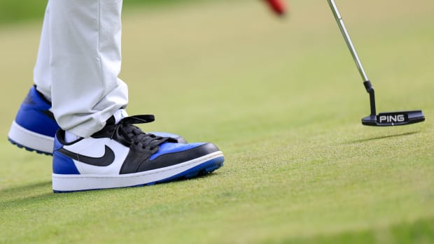 Side view of white, black, and blue Air Jordan golf shoes.