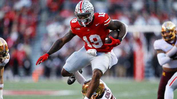 Ohio State Buckeyes running back Chip Trayanum (19) hurdles Minnesota Golden Gophers defensive back Tre'Von Jones (2) during the first quarter at Ohio Stadium.