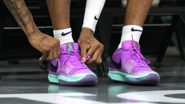 Memphis Grizzlies guard Ja Morant ties his purple Nike sneakers before a game.