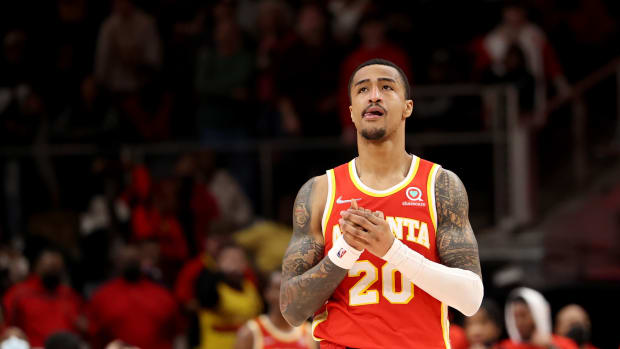 Atlanta Hawks forward John Collins clasps his hands while walking down the court.