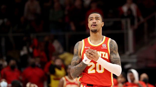Hawks forward John Collins clasps his hands while walking down the court.