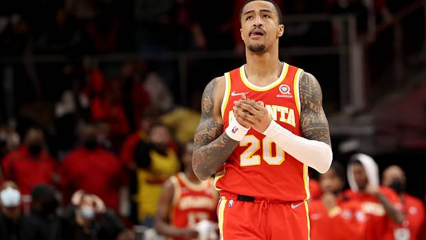 Hawks forward John Collins clasps his hands while walking down the court.