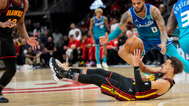Apr 13, 2022; Atlanta, Georgia, USA; Atlanta Hawks guard Trae Young (11) passes the ball from the floor to forward De'Andre Hunter (12) behind Charlotte Hornets forward Miles Bridges (0) during the second half at State Farm Arena.