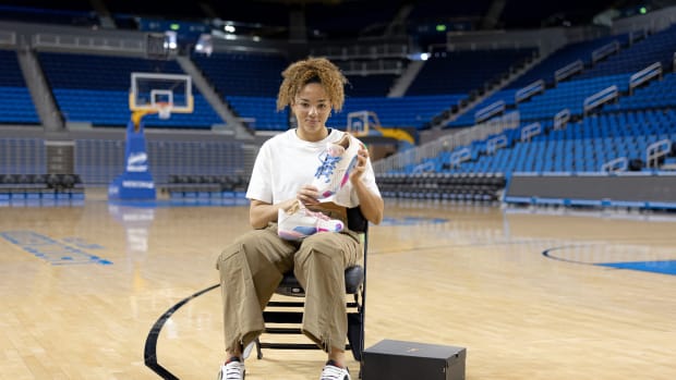 Kiki Rice holds up Air Jordan sneakers on the UCLA Bruins basketball court.