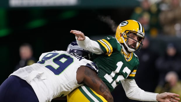 Green Bay Packers quarterback Aaron Rodgers (12) throws the ball as he is hit by Seattle Seahawks defensive tackle Quinton Jefferson (99) in the first quarter of a NFC Divisional Round playoff football game at Lambeau Field.