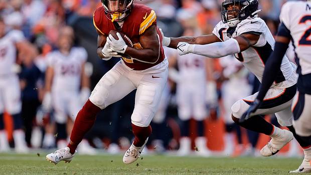 Washington Commanders running back Antonio Gibson (24) runs through the tackle of Denver Broncos linebacker Jonathon Cooper (0) in the fourth quarter at Empower Field at Mile High.