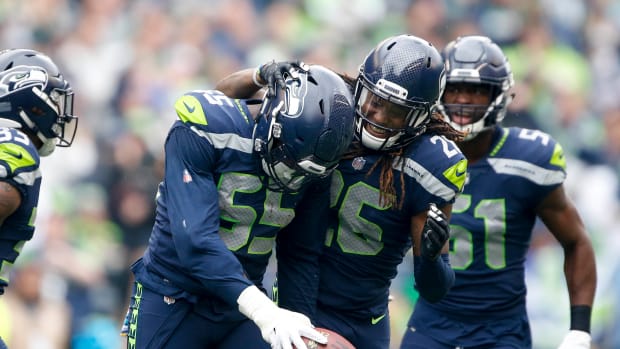 Seattle Seahawks defensive end Frank Clark (55) celebrates with cornerback Shaquill Griffin (26) after catching an interception against the Los Angeles Rams during the first quarter at CenturyLink Field.