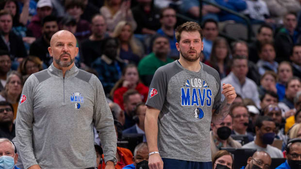 Luka Doncic stands beside Jason Kidd on the sidelines.