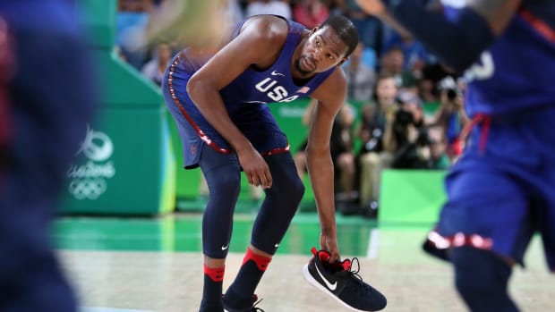 Team USA forward Kevin Durant picks up his shoe during a game.