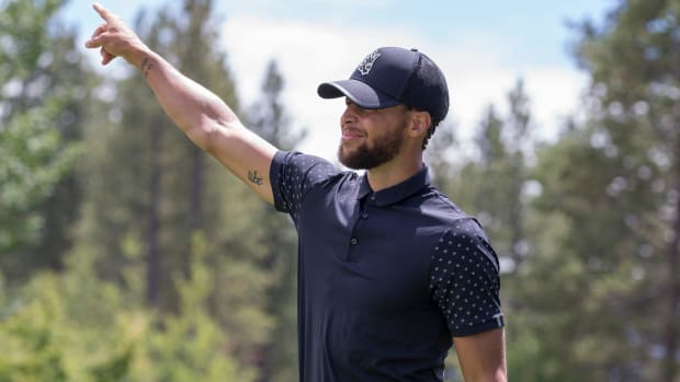 Stephen Curry reacts to a shot on a golf course.
