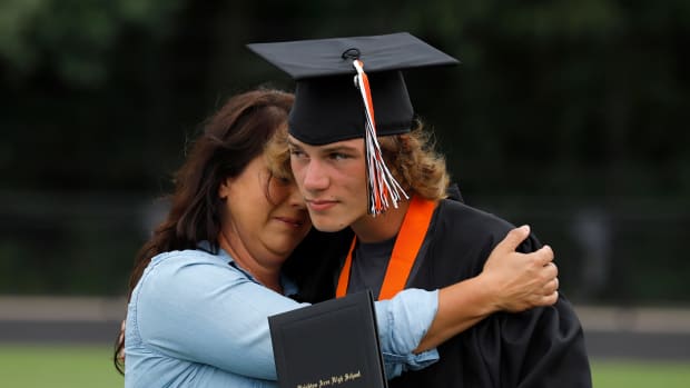 Graduate Reagan Murphy gets a hug from mom, Jessica following Brighton's outdoor socially distanced graduation ceremony at their football stadium, Saturday, Aug. 01, 2020, in Brighton, Mich.