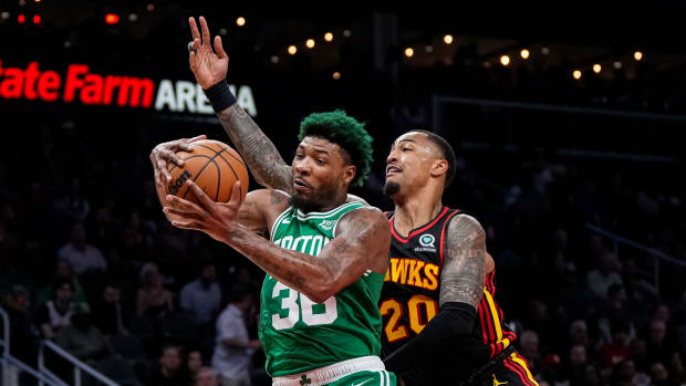 Boston Celtics guard Marcus Smart gets a rebound over Atlanta Hawks forward John Collins.