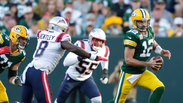 Green Bay Packers quarterback Aaron Rodgers runs the ball against New England Patriots defenders.