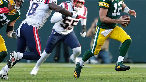 Green Bay Packers quarterback Aaron Rodgers runs the ball against New England Patriots defenders.