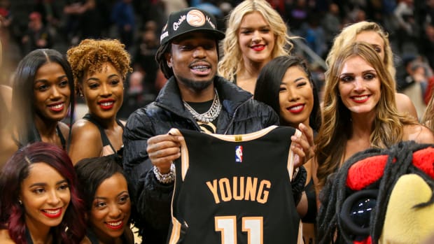 Rapper Quavo celebrates with cheerleaders while holding the jersey of Atlanta Hawks guard Trae Young (not pictured) after a victory against the Miami Heat at State Farm Arena.